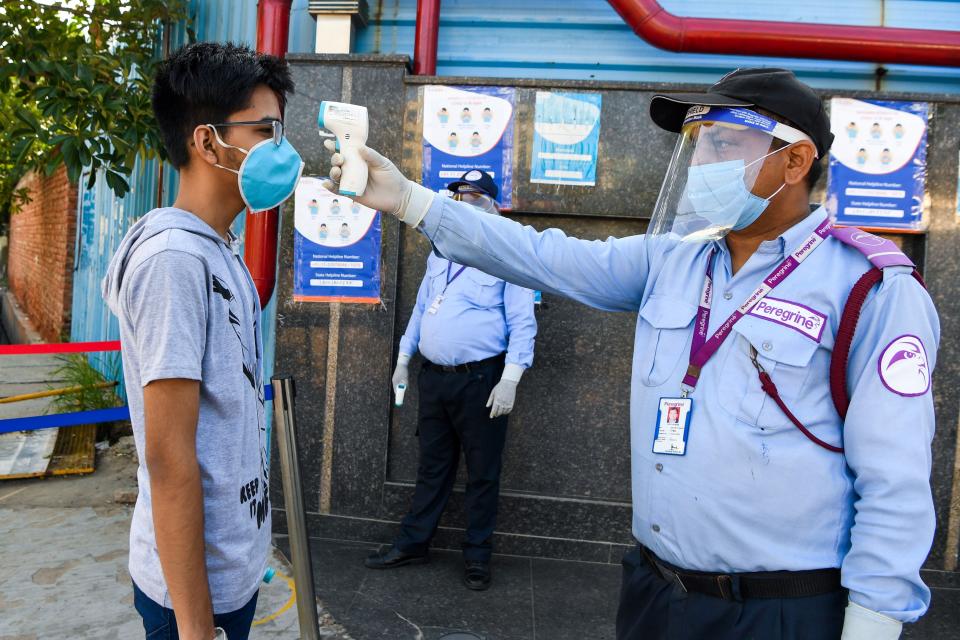 A student gets her temperature taken as he arrives at an examination centre for Joint Entrance Examination (JEE ) Main-2020, one of the most competitive entrance exams for entry to top national engineering colleges, in Noida on September 1, 2020. (Photo by Prakash SINGH / AFP) (Photo by PRAKASH SINGH/AFP via Getty Images)