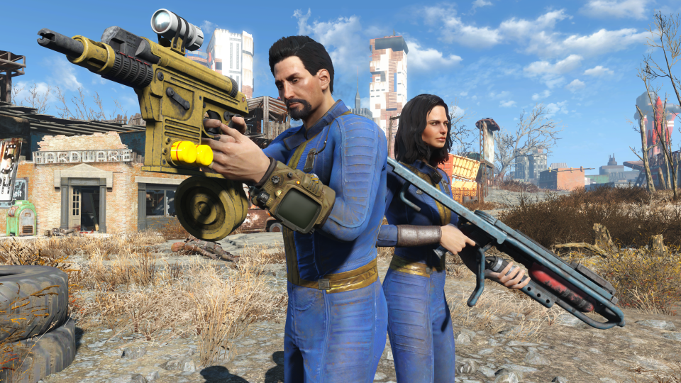 Captura de pantalla promocional de la actualización de la consola de próxima generación para Fallout 4. Dos personas (con traje azul) están armadas con armas de fuego en un páramo de videojuegos.  Edificios en ruinas y un paisaje desértico al fondo.