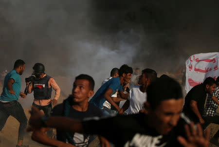 Palestinian demonstrators run for cover from tear gas fired by Israeli troops during a protest demanding the right to return to their homeland at the Israel-Gaza border, in the southern Gaza Strip August 3, 2018. REUTERS/Ibraheem Abu Mustafa