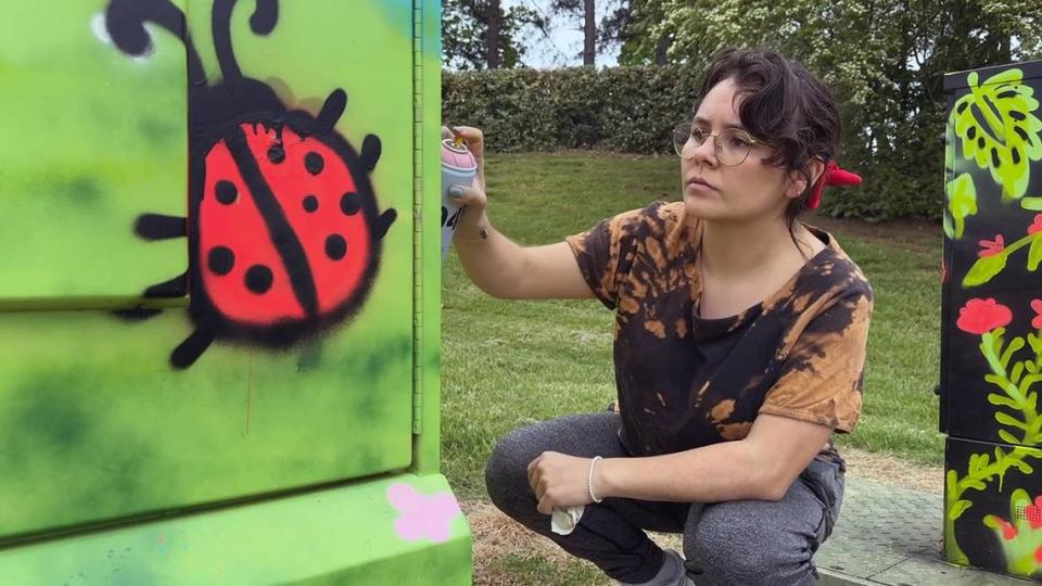 Queens University student Ana Garay paints a utility box at Pineville Lake Park.
