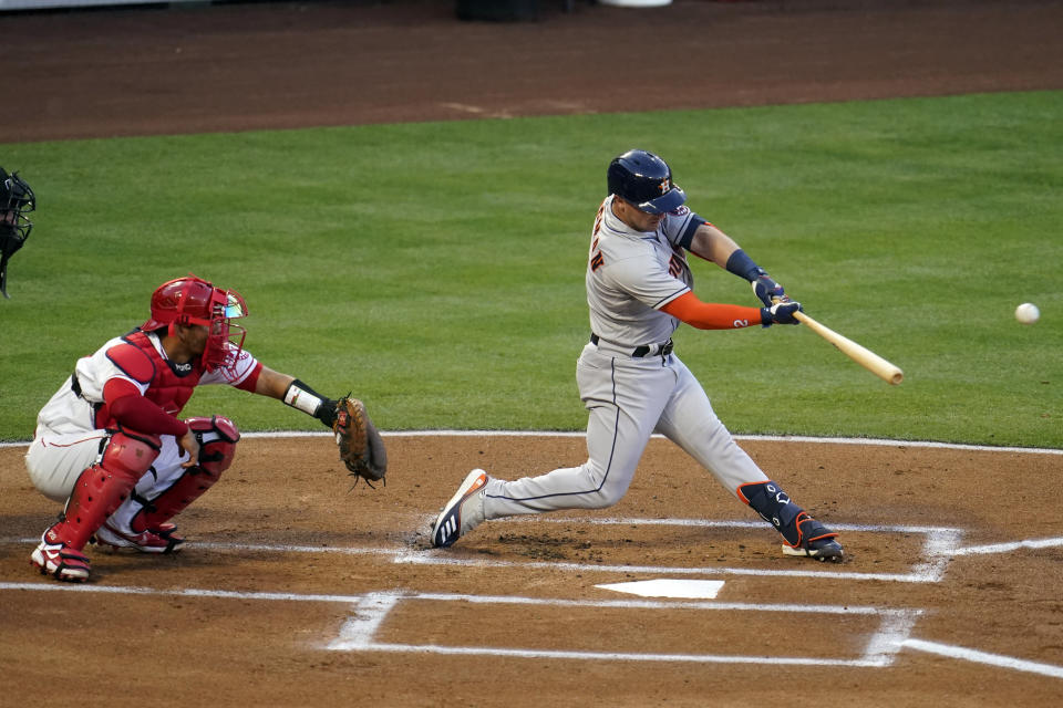 Houston Astros third baseman Alex Bregman, right, drives in a run with a single during the first inning of a baseball game against the Los Angeles Angels, Monday, April 5, 2021, in Anaheim, Calif. (AP Photo/Marcio Jose Sanchez)