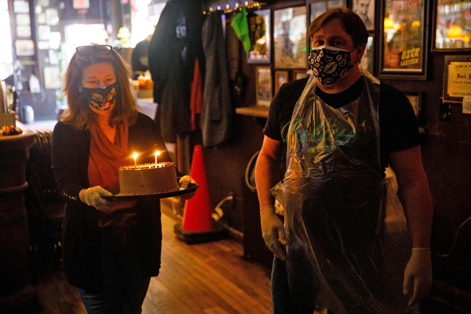 Helen Buford, owner of Julius', carries a birthday cake alongside Gerry Gonzalez to Bronwyn Rucker and Jimmy Tomkins, longtime customers who were celebrating their birthdays on March 19. (Julius Constantine Motal / NBC News)