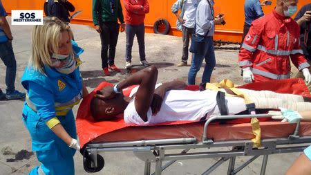 A migrant receives help when disembarking from the SOS Mediterranee ship Aquarius at the Italian island of Lampedusa in this handout received April 18, 2016. SOS Mediterranee/Handout via REUTERS