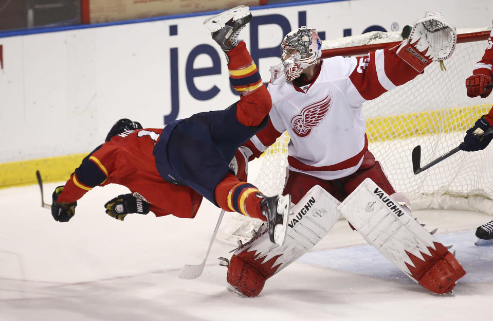 After hitting Detroit Red Wings goalie Jimmy Howard's (35) stick, Florida Panthers' Jesse Winchester falls to the ice during the third period of a NHL hockey game in Sunrise, Fla., Tuesday, Dec. 10, 2013. The Panthers won 3-2 in a shootout during overtime. (AP Photo/J Pat Carter)