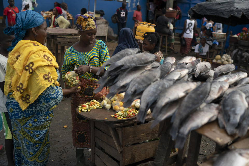 A woman sells her goods at a local market in Abobo neighborhood, suburbs of Abidjan, Ivory Coast, Sunday, Nov. 1, 2020. Ivory Coast's main opposition parties boycotted the presidential vote on Saturday, and asserted that at least a dozen people had died in election day clashes as incumbent leader Alassane Ouattara sought to be elected for a controversial third term in office. (AP Photo/Leo Correa)