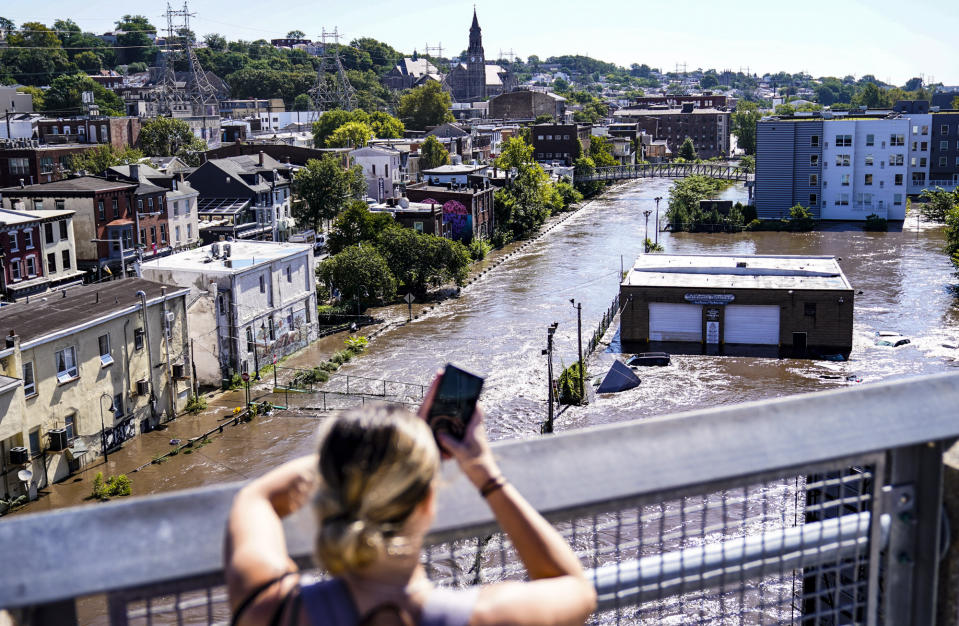 FILE - A person takes a photo of the Schuylkill River after it flooded the Manayunk section of Philadelphia in the aftermath of Hurricane Ida on Thursday Sept. 2, 2021. As weather becomes more extreme and unpredictable caused by climate change, transit officials say that more needs to be done to prepare the East Coast's vital transit systems. (AP Photo/Matt Rourke, File)