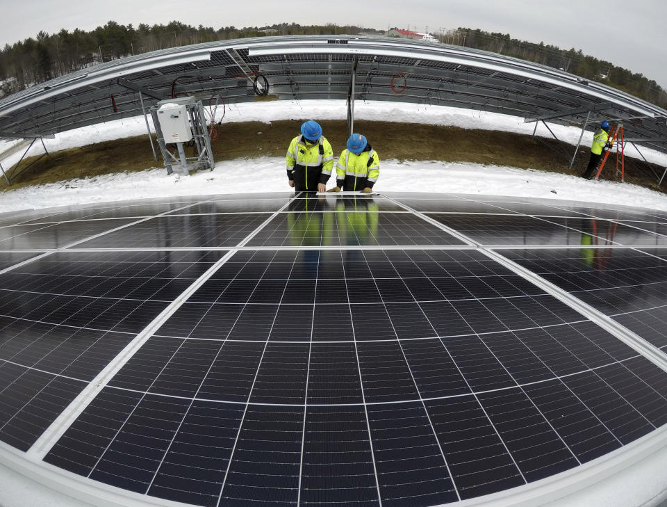 Electricians Bryan Driscoll and Zach Newton and consult a wiring schematic while installing solar panels at the 38-acre BNRG/Dirigo solar farm, Thursday, Jan. 14, 2021, in Oxford, Maine. President Joe Biden wants to change the way the U.S. uses energy by expanding renewables, but faces several challenges. (AP Photo/Robert F. Bukaty)