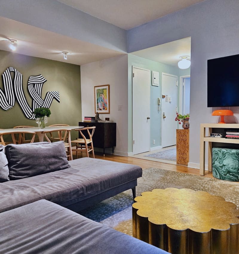 blue living room with gray sofa and cloud shaped gold table. View into dining room