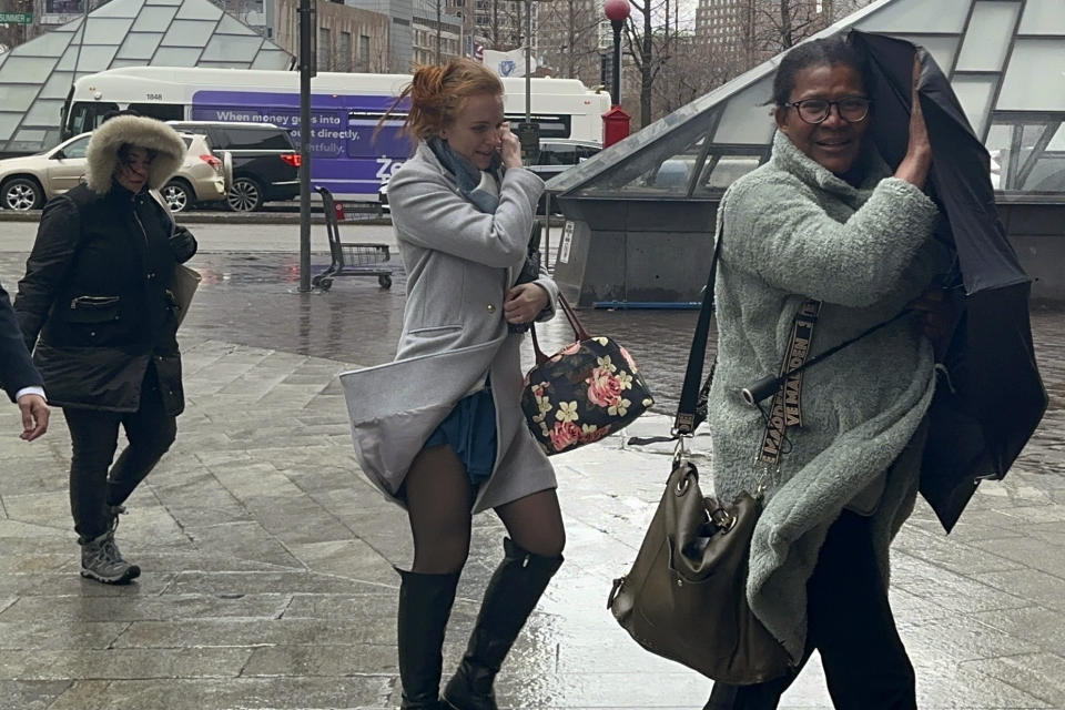 A commuter struggles with her umbrella while walking through wind-driven rain near South Station, Thursday, April 4, 2024, in Boston. (AP Photo/Nick Perry)