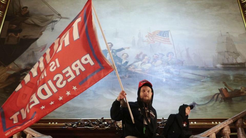 Los manifestantes creen -sin pruebas- que Trump ganó las elecciones en noviembre. Este lleva una bandera que dice "Trump es mi presidente".