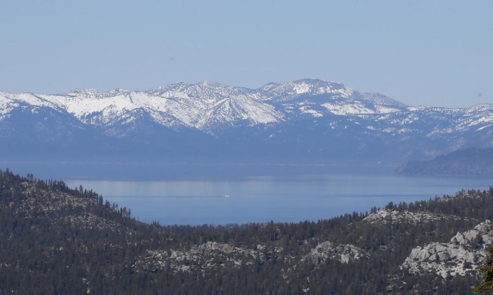 A picturesque landscape shows Lake Tahoe with its snow-capped mountains in the distance.