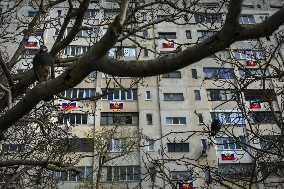 FILE - In this Friday, March 14, 2014 file photo, Russian flags are hung from an apartment building in a residential district in Sevastopol, Ukraine. Despite the pebble beaches and cliff-hung castles that made Crimea famous as a Soviet resort hub, the Black Sea peninsula has long been a corruption-riddled backwater in economic terms. The Kremlin, which decided to take the region from Ukraine after its residents voted in a referendum to join Russia, has begun calculating exactly what it will cost to support Crimea’s shambolic economy _ which one Russian minister described as “no better than Palestine.” (AP Photo/Andrew Lubimov, File)