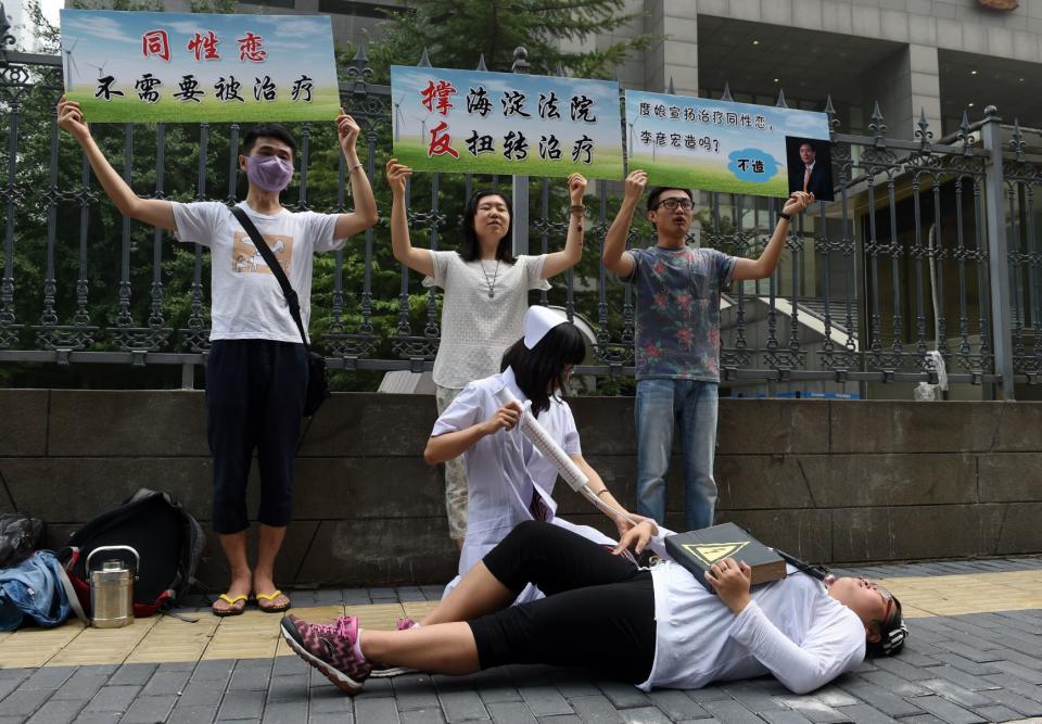 Xiao Tie, executive director of the Beijing LGBT Centre, pretends to inject a patient with a mock syringe during a protest outside the Haidian District Court in Beijing on July 31, 2014. The court began hearing a landmark case on "gay conversion" treatment July 31, as an activist in a nurse's uniform knelt over a patient, wielding a giant needle, outside.
