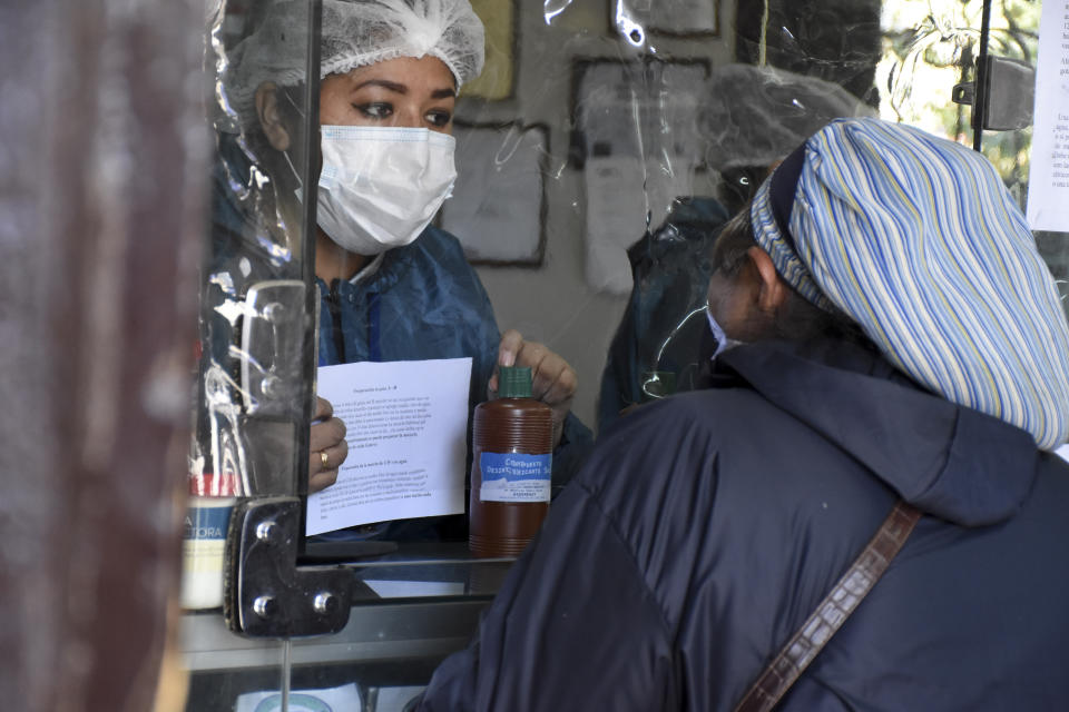 A woman buys chlorine dioxide at a pharmacy in Cochabamba, Bolivia, Friday, July 17, 2020. Long lines form every morning in Cochabamba, one of the Bolivian cities hardest hit by the new coronavirus pandemic, as people wait to buy small bottles of chlorine dioxide, a toxic bleaching agent that has been falsely touted as a cure for COVID-19 and myriad other diseases. (AP Photo/Dico Solis)