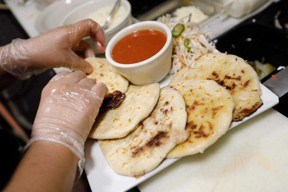 Flor Flores puts the final touches on the pupusas she made at Mi Antojo restaurant on South Sixth Street in New Bedford.
