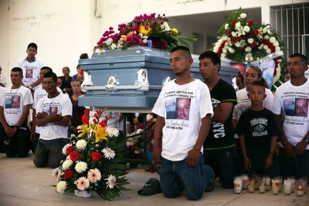 Relatives of Antonio Zambrano-Montes kneel next to his coffin during a funeral mass in Pomaro, in the Mexican state of Michoacan March 7, 2015. Zambrano-Montes, 35, an unemployed orchard worker from Mexico's Michoacan state, was killed in February in Pasco, a city of 68,000 residents in Washington state's agricultural heartland. REUTERS/Alan Ortega/File Photo