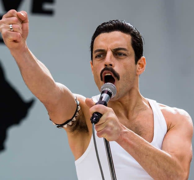 Rami Malek acting as Freddie Mercury and singing into a mic