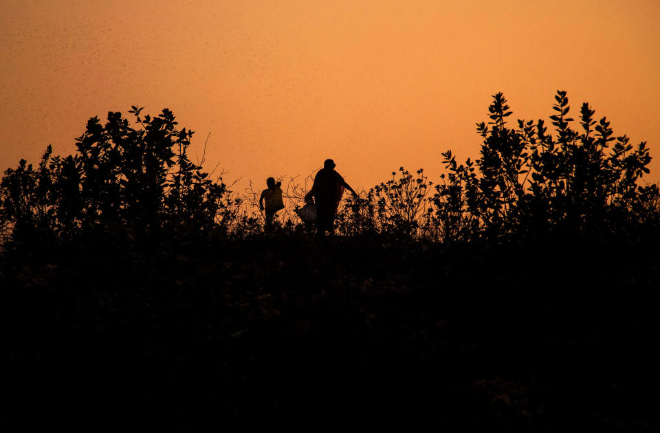 Imradul Ali, 10, left, and his mother Anuwara Beghum, 30, return after collecting recyclable materials from a landfill on the outskirts of Gauhati, India, Thursday, Feb. 4, 2021. Once school is done for the day, Ali, rushes home to change out of his uniform so that he can start his job as a scavenger in India’s remote northeast. Coming from a family of scavengers or “rag pickers," Ali started doing it over a year ago to help his family make more money. Ali says he doesn’t want to spend his life doing this, but he doesn’t know what the future holds. (AP Photo/Anupam Nath)