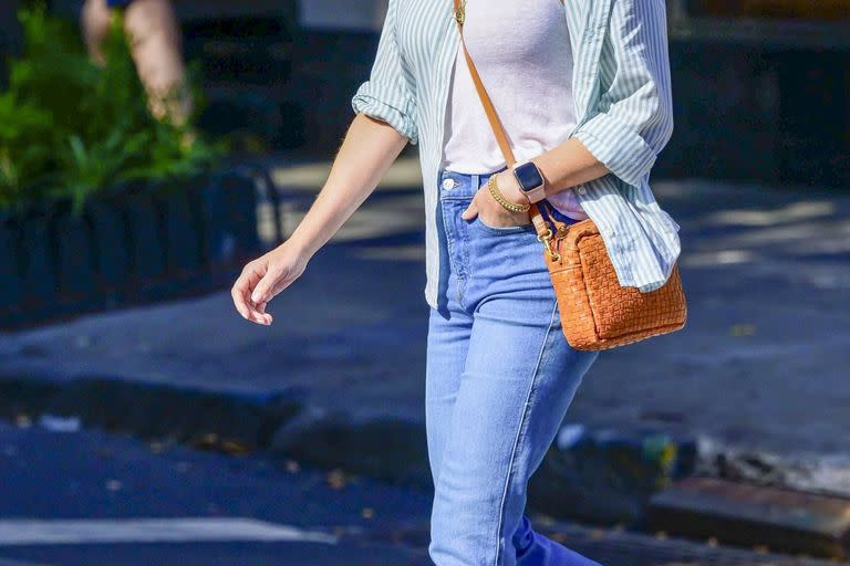 Reese Witherspoon eligió un look súper canchero para ir de compras con su hijo. La actriz combinó unos jeans azules con una musculosa básica blanca y una camisa rayada que usó desabrochada. Su cartera en color suela le dio un toque de color a su outfit