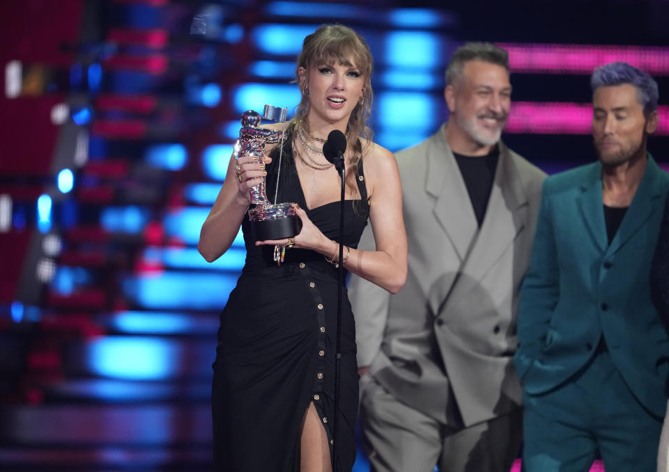 Taylor Swift recibe el premio a mejor pop por "Anti-Hero" en los Premios MTV a los videos musicales el martes 12 de septiembre de 2023 en el Prudential Center en Newark, Nueva Jersey. Joey Fatone, centro, y Lance Bass ven desde la derecha. (Foto Charles Sykes/Invision/AP)