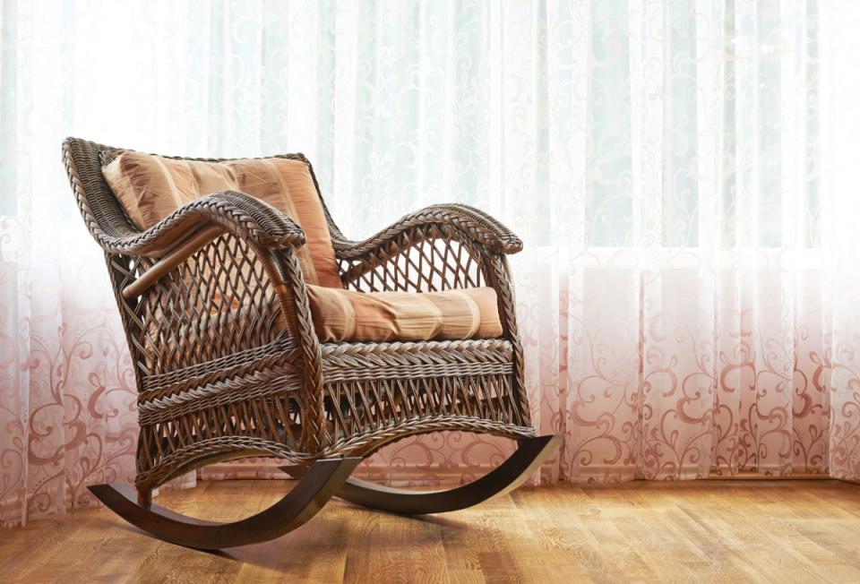 Rocking chair in home with pinkish sheer curtains in background