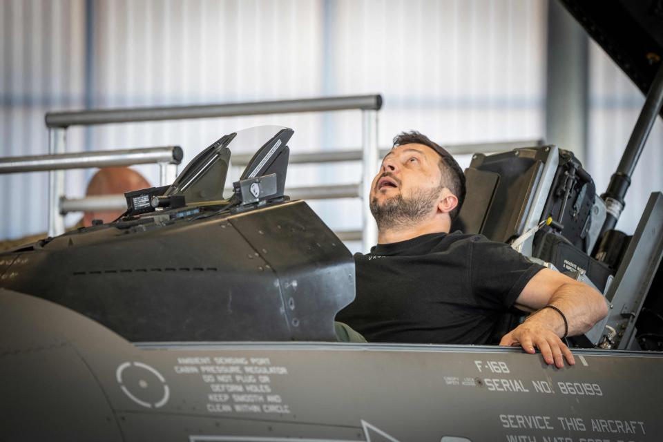 Ukrainian President Volodymyr Zelenskyy looks up while sitting in an F-16 fighter jet