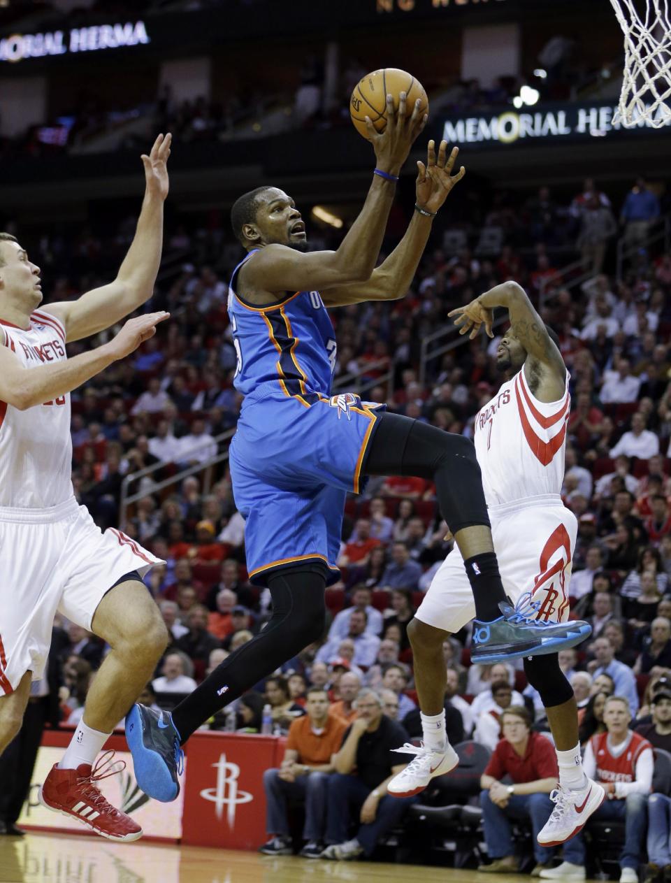 Oklahoma City Thunder's Kevin Durant, center, goes up for a shot as Houston Rockets' Aaron Brooks (0) and Donatas Motiejunas (20) defend during the first quarter of an NBA basketball game, Thursday, Jan. 16, 2014, in Houston. Durant was fouled by Brooks on the play. (AP Photo/David J. Phillip)