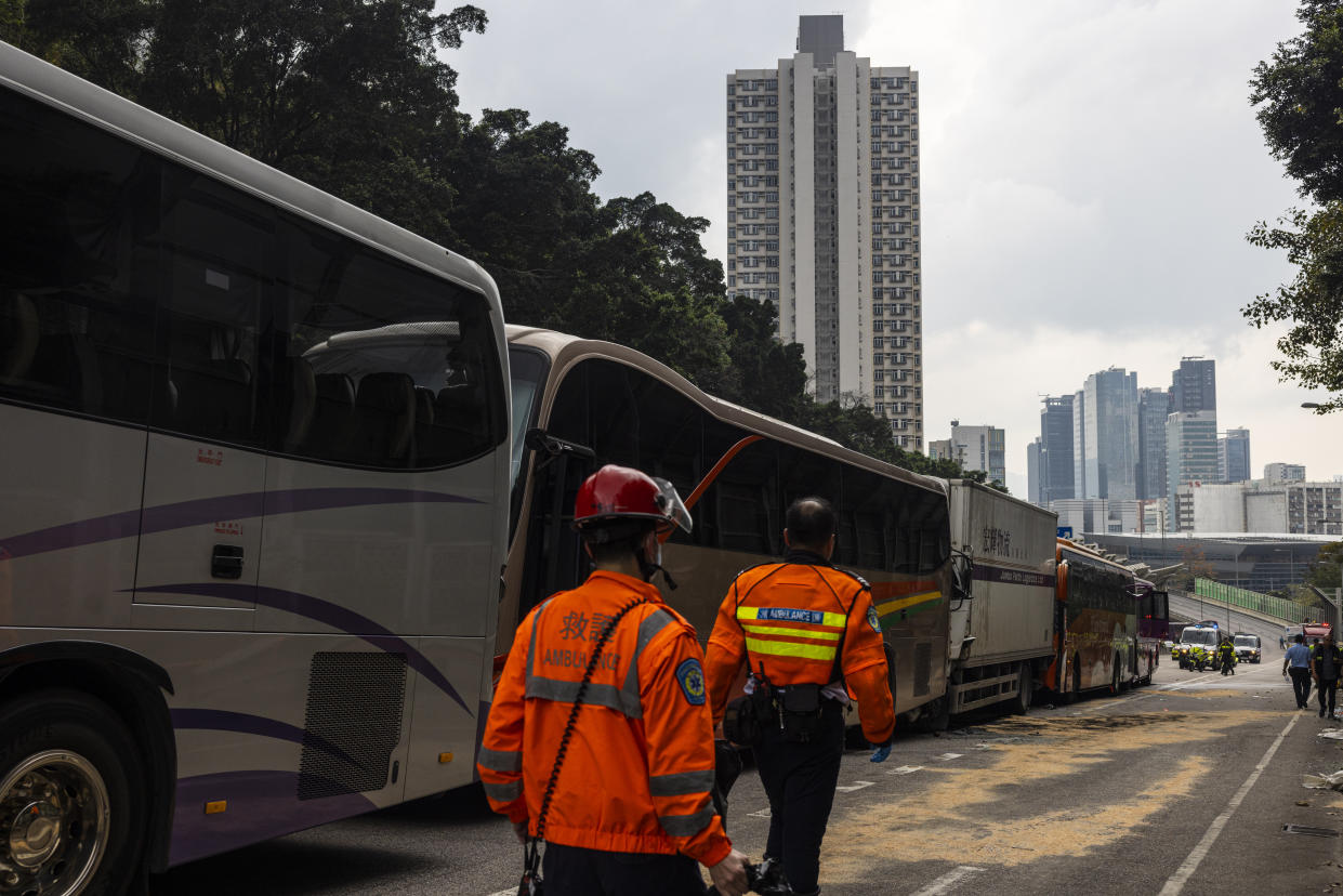 Ambulance workers inspect after an accident on a highway in Hong Kong, Friday, March 24, 2023. Four passenger buses and a truck collided near a Hong Kong road tunnel Friday, injuring dozens of people. (AP Photo/Louise Delmotte)