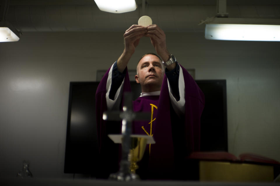 Navy Chaplain Lt. Cmdr. Ben Garrett performs the sacrament of the Eucharist in the chapel of the USS Bataan on Wednesday, March 15, 2023 at Norfolk Naval Station in Norfolk, Va. Before joining the U.S. Navy, Chaplain Garrett was a priest in Washington DC. (AP Photo/John C. Clark)