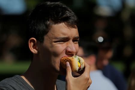 A man eats a hot dog as he attends a celebration marking the opening of a new exhibit at Ellis Island highlighting the immigrant history behind the "Hot Dog" in New York City, U.S., June 28, 2017. REUTERS/Lucas Jackson