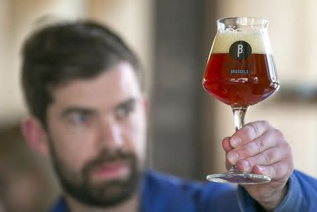 Sebastien Morvan, one of the founders of microbrewery Brussels Beer Project, inspects a glass of Babylone beer at Barbeton bar in central Brussels, April 14, 2015. REUTERS/Yves Herman