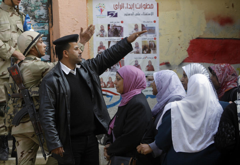 An Egyptian army soldier and a policeman direct voters in front of a polling station in Cairo, Egypt, Tuesday, Jan. 14, 2014. Egyptians have started voting on a draft for their country's new constitution that represents a key milestone in a military-backed roadmap put in place after President Mohammed Morsi was overthrown in a popularly backed coup last July. Arabic reads " steps for voting." (AP Photo/Amr Nabil)