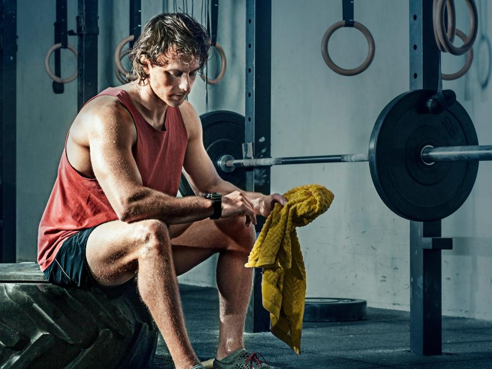 an athlete on a weightlifting bench checking a watch between sets