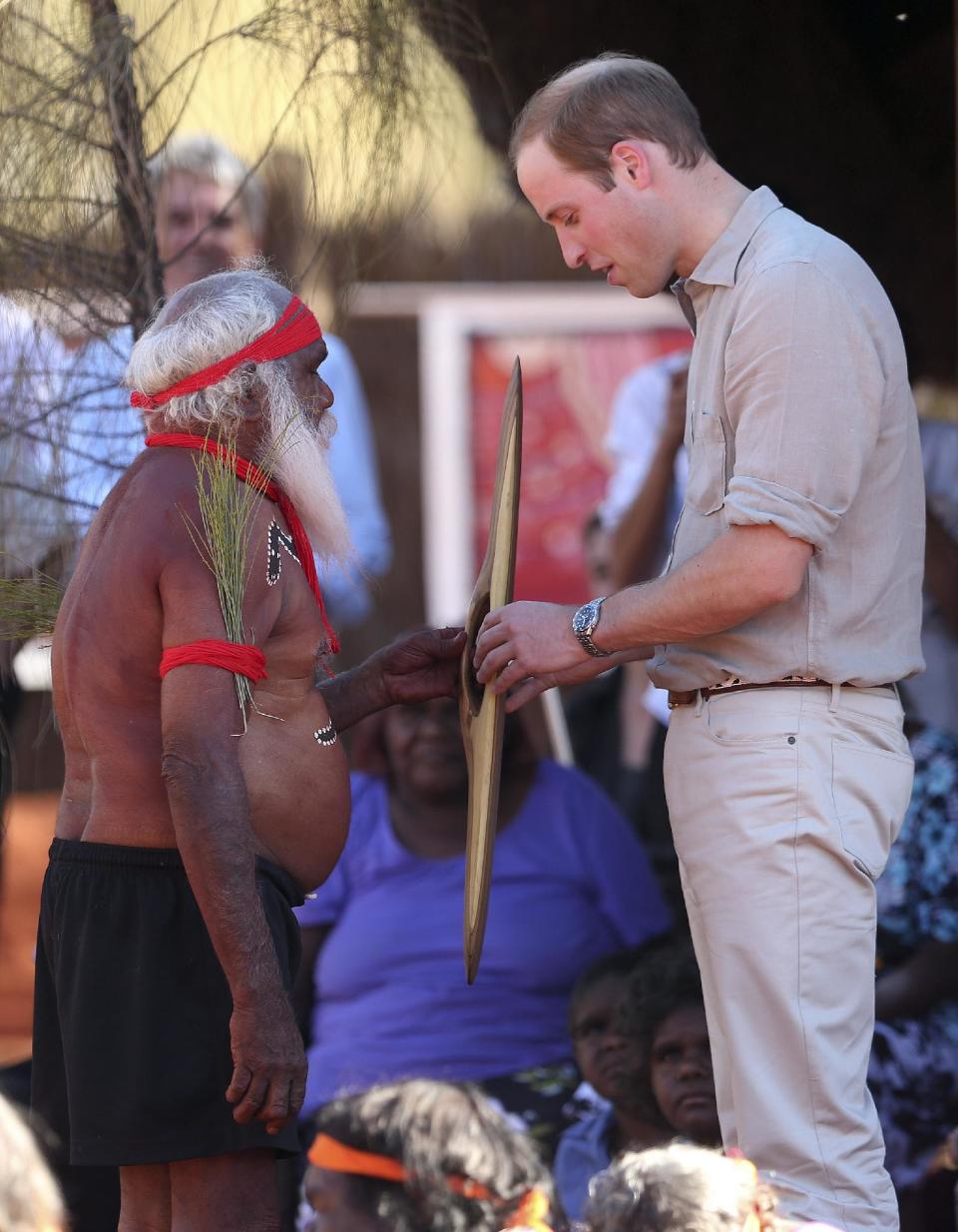 Britain's Prince William, right, receives a gift from a local aboriginal community man during a welcome ceremony at the Uluru Cultural Center in Uluru, Australia, Tuesday, April 22, 2014. (AP Photo/Rob Griffith)