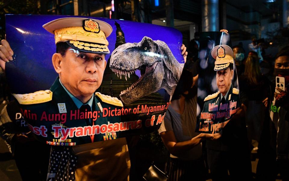 A protester holds a banner with the image of Myanmar military chief General Min Aung Hlaing and a dinosaur, as they take part in a demonstration condemning the military coup - MLADEN ANTONOV /AFP