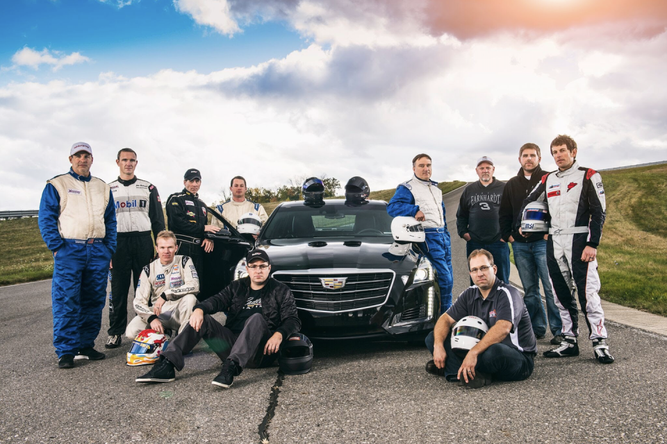 a group of people posing for a photo next to a car