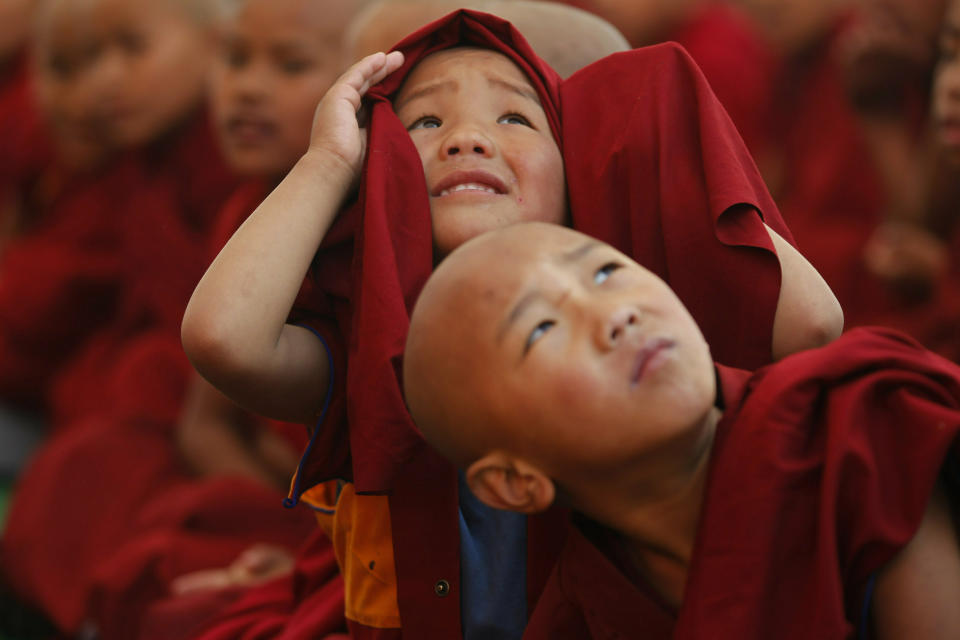 In this Wednesday, Feb. 13, 2019, file photo, young monks get distracted by a drone as they watch a traditional dance during Cham dance festival as part of Tibetan New Year celebrations, at the Triten Norbutse Monastery in Kathmandu, Nepal. According to Bön Tibetan Buddhism, this mask dance is a purification ceremony that eliminates negative energy and bad luck in the beginning of the new year. (AP Photo/Niranjan Shrestha, File)