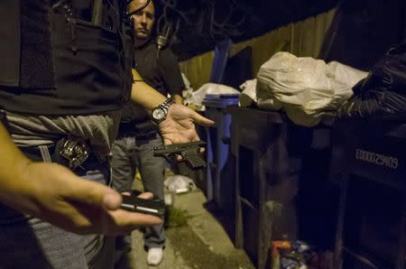 Cook County Sheriff police officers find a handgun hidden among the trash cans in an alley in the Austin neighborhood in Chicago, Illinois, United States, September 9, 2015. REUTERS/Jim Young