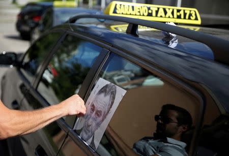 A taxi driver sticks a poster of Robert De Niro on a cab in tribute to the actor who will open the city's film festival on Friday with a screening of "Taxi Driver" in Sarajevo, Bosnia and Herzegovina, August 12, 2016. REUTERS/Dado Ruvic