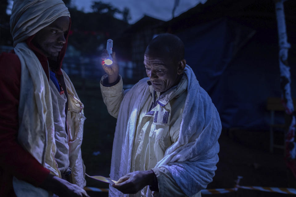 Ethiopian official checks voting card of a voter before he casts his vote in the general election in his home town of Beshasha, in the Oromia region of Ethiopia, Monday, June 21, 2021. Ethiopians are voting in a landmark election that is the centerpiece of a reform drive by Prime Minister Abiy Ahmed but is overshadowed by the situation in the country's war-hit Tigray region. (AP Photo/Mulugeta Ayene).