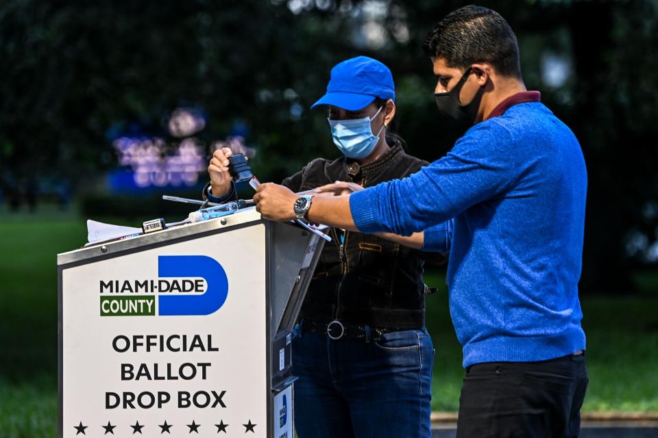 A poll worker helps a voter put as she drops off her mail-in ballot at an official Miami-Dade County drive-thru ballot drop box at the Miami-Dade County Election Department in Miami, on Nov. 3, 2020.