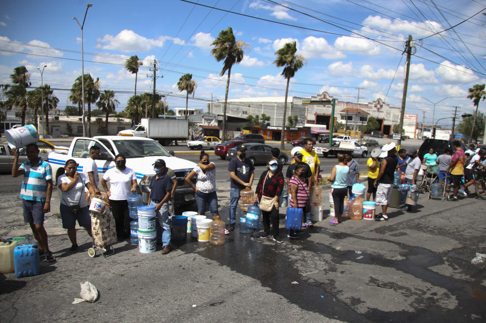 Neighbors wait in line to collect water in plastic containers at a public collection point in Monterrey, Mexico, Monday, June 20, 2022. Local authorities began restricting water supplies in March, as a combination of an intense drought, poor planning and high use has left the three dams that help supply the city dried up, with thousands of homes not receiving any water for weeks. (AP Photo)