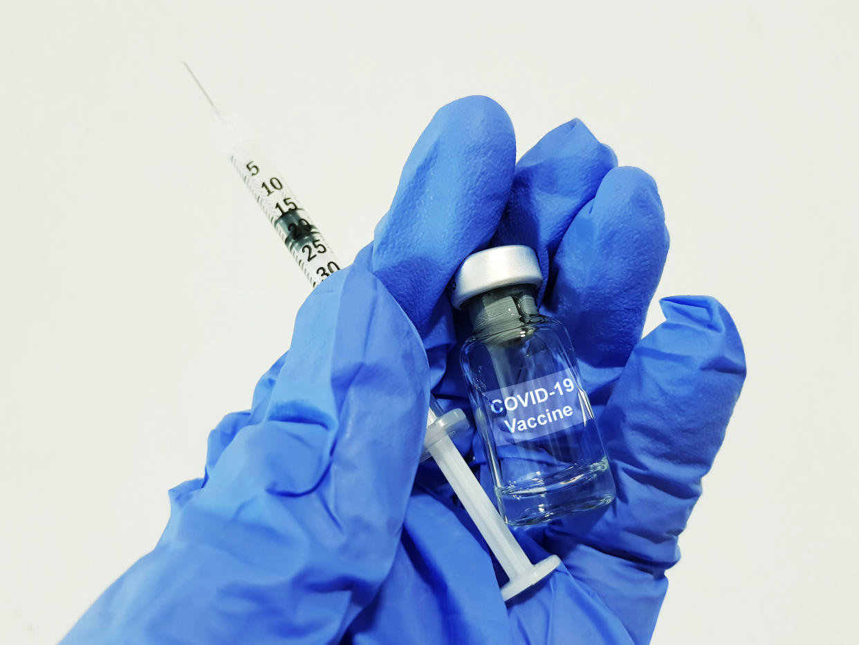 Covid-19 Coronavirus Vaccine. Hand wearing glove, holding a vial and syringe