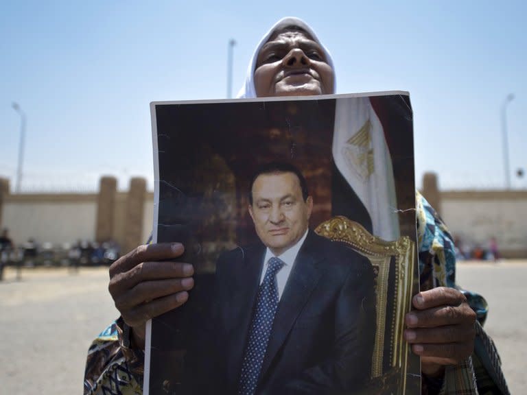 A supporter of former Egyptian president Hosni Mubarak, holds a portrait of him outside the Egyptian police academy in Cairo, where his trial is taking place, May 11, 2013. Mubarak, on trial for the death of protesters during Egypt's 2011 uprising that toppled him, said future generations would judge him "fairly" in an interview published on Sunday