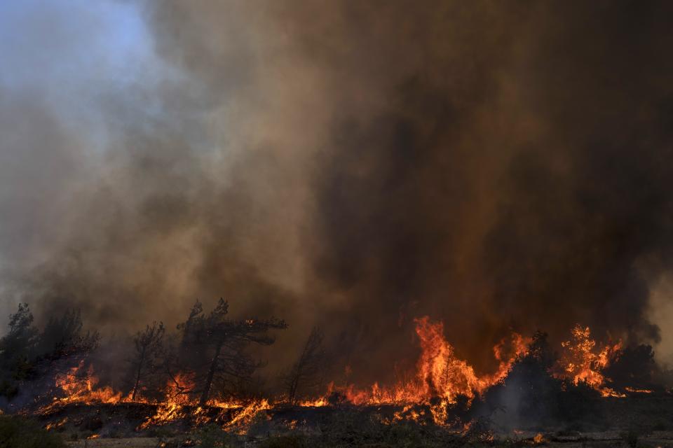 Flames burn a forest during a wildfire in Vati village, on the Aegean Sea island of Rhodes, southeastern Greece, on Tuesday, July 25, 2023. A third successive heat wave in Greece pushed temperatures back above 40 degrees Celsius (104 degrees Fahrenheit) across parts of the country Tuesday following more nighttime evacuations from fires that have raged out of control for days. (AP Photo/Petros Giannakouris)