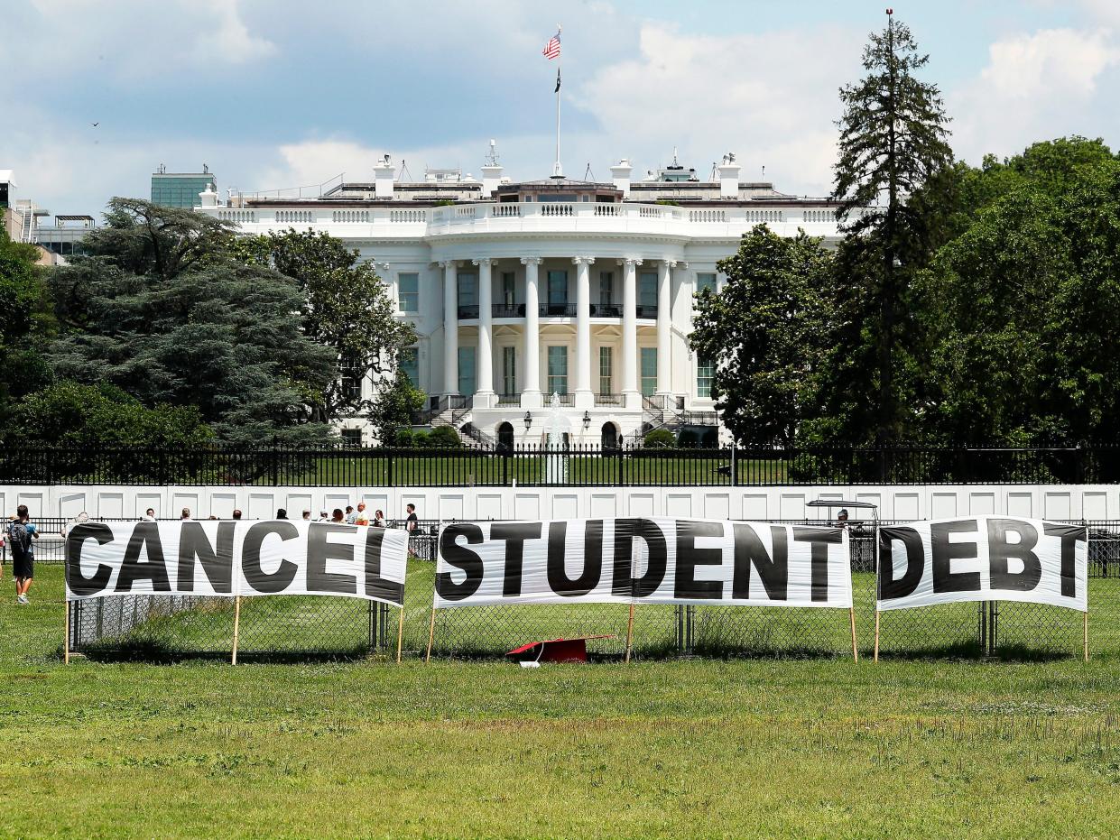 A hand-written sign reading "Cancel Student Debt" is held up and the White House is seen in the background.