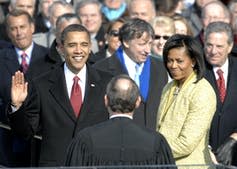 Obama smiles with his right hand raised as he takes the oath of office at his inauguration.