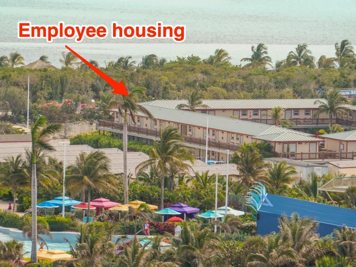 An arrow points to employee housing with palm trees between them and ocean waters in the background