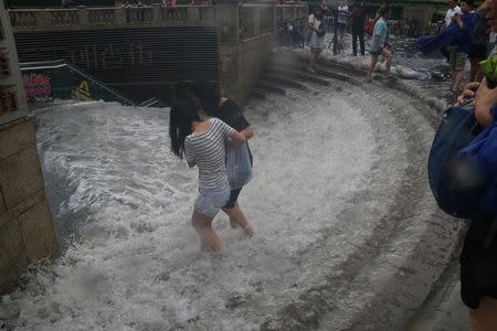 People walk into a flooded subway station in Tianjin, China, July 20, 2016. Picture taken July 20, 2016. REUTERS/Stringer