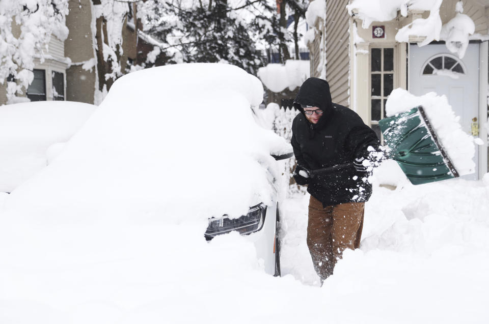 Mike Sweeney tries to clear snow away from his girlfriend's Volkswagen Tiguan outside their home in Buffalo, N.Y.'s Elmwood Village on Monday, Dec. 26, 2022. The couple has been out of power since Friday, Dec. 23, due to the blizzard. (Joseph Cooke/The Buffalo News via AP)